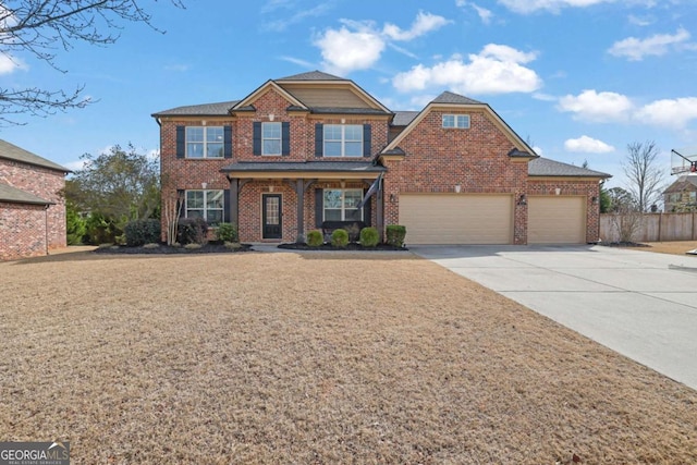 view of front of house with a garage, concrete driveway, brick siding, and fence