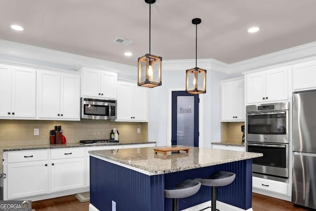 kitchen with hanging light fixtures, a kitchen island, white cabinetry, and stainless steel appliances