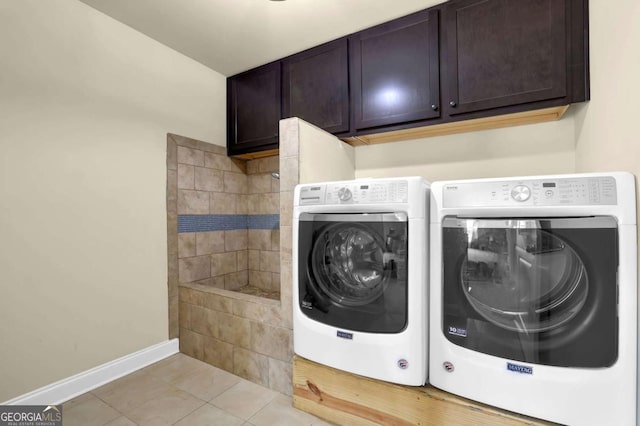 washroom with light tile patterned floors, washing machine and clothes dryer, cabinet space, and baseboards