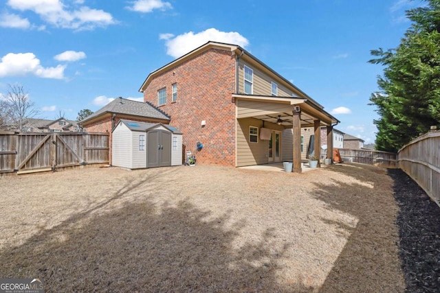 rear view of house with a ceiling fan, a fenced backyard, a storage unit, a patio area, and brick siding