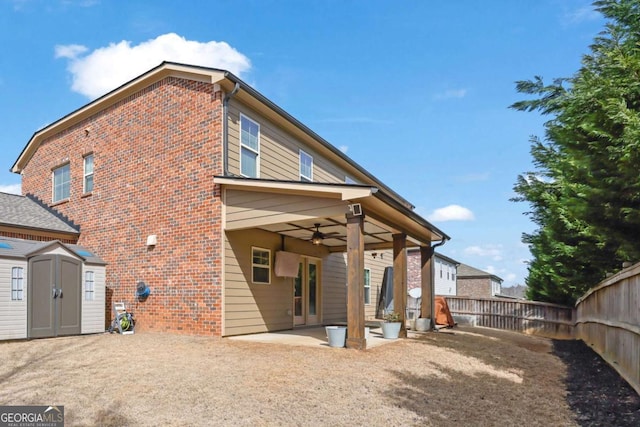 rear view of house with an outbuilding, a storage shed, brick siding, a ceiling fan, and a patio area