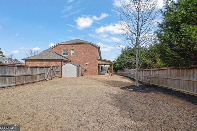 rear view of property featuring an outbuilding, a storage unit, a fenced backyard, and brick siding