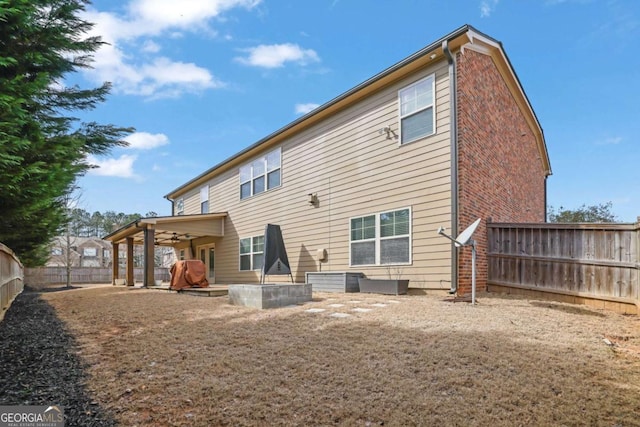 rear view of property featuring brick siding and a fenced backyard