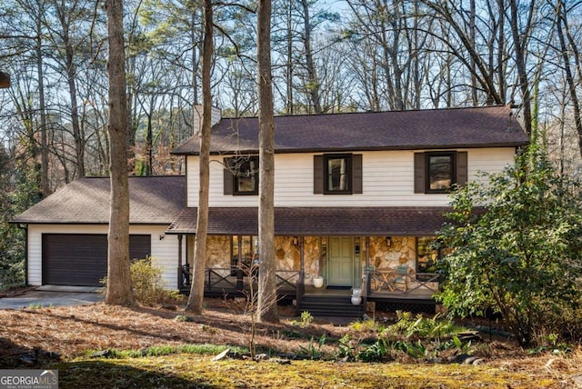 view of front of house featuring a porch, an attached garage, stone siding, driveway, and a chimney