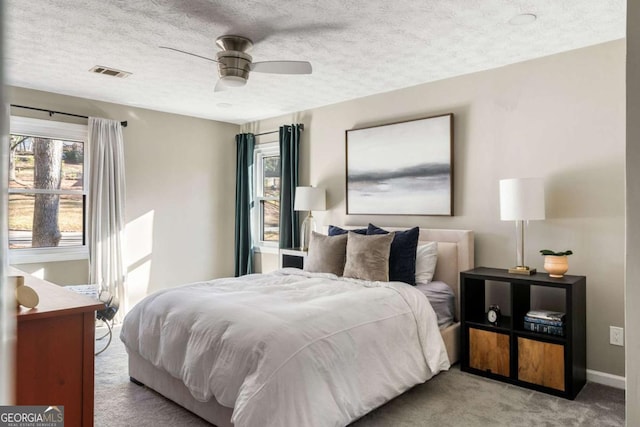 carpeted bedroom with visible vents, ceiling fan, a textured ceiling, and baseboards