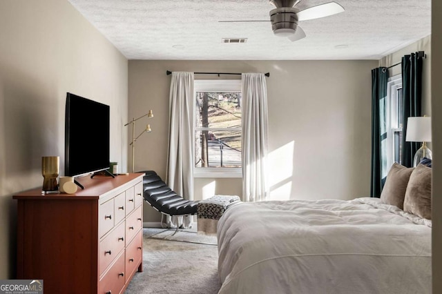 bedroom featuring carpet flooring, ceiling fan, visible vents, and a textured ceiling