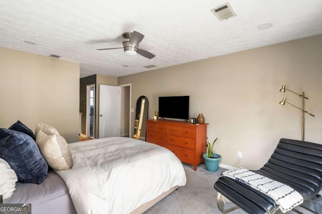 bedroom with carpet floors, a ceiling fan, visible vents, and a textured ceiling