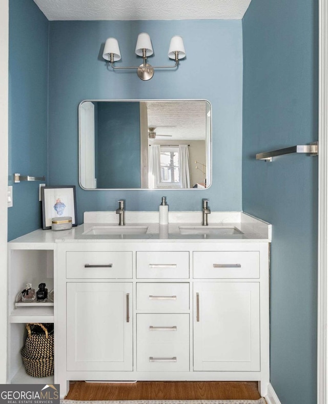 full bathroom with a sink, a textured ceiling, and double vanity