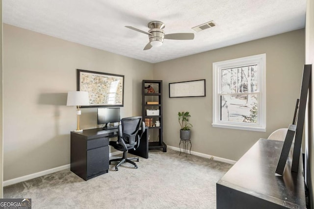 carpeted office space featuring a textured ceiling, a ceiling fan, visible vents, and baseboards