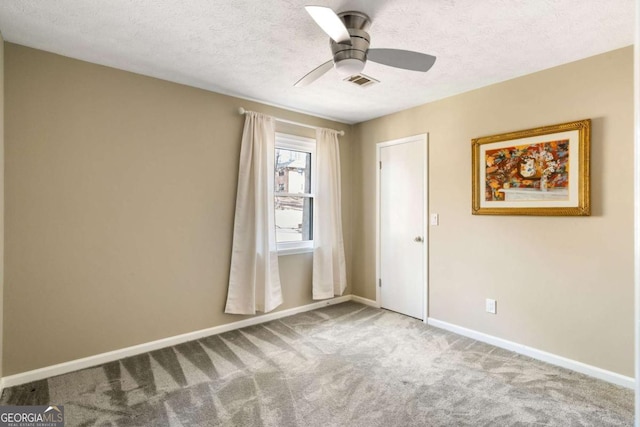 carpeted spare room featuring a textured ceiling, a ceiling fan, visible vents, and baseboards