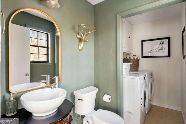 half bathroom featuring toilet, a sink, baseboards, tile patterned floors, and washing machine and clothes dryer