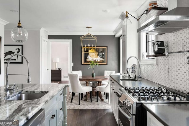 kitchen featuring dark wood-type flooring, wall chimney range hood, stainless steel gas range, and a sink