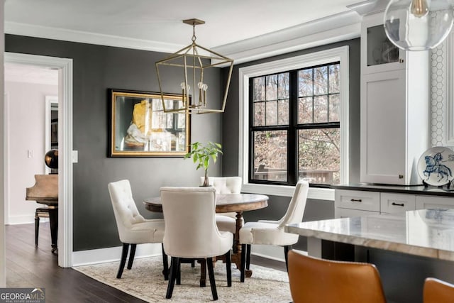 dining space featuring dark wood-style floors, crown molding, a chandelier, and baseboards