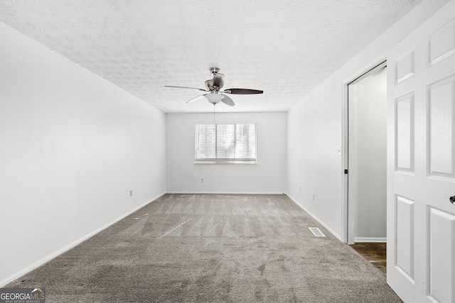 spare room featuring a textured ceiling, carpet flooring, a ceiling fan, and baseboards