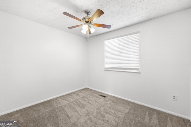 carpeted empty room with a ceiling fan, visible vents, a textured ceiling, and baseboards