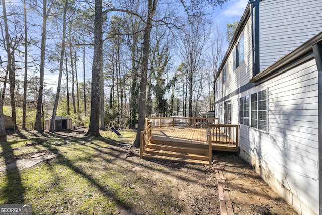 view of yard featuring an outbuilding, a wooden deck, and a storage shed