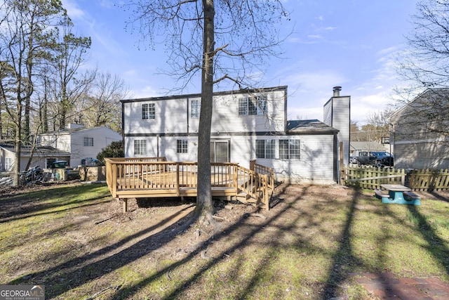 rear view of property with a chimney, a lawn, fence, driveway, and a wooden deck