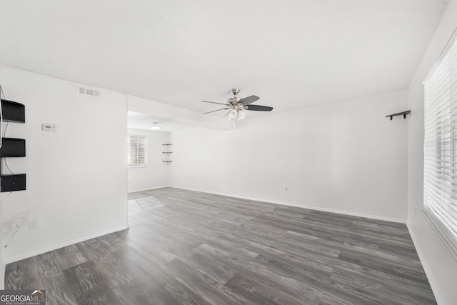 spare room featuring dark wood-style floors, ceiling fan, visible vents, and a wealth of natural light