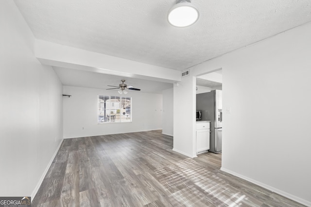 unfurnished living room with visible vents, ceiling fan, light wood-style flooring, and a textured ceiling