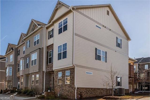 view of side of home featuring central AC, brick siding, and board and batten siding