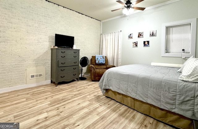 bedroom with ceiling fan, brick wall, light wood finished floors, and visible vents