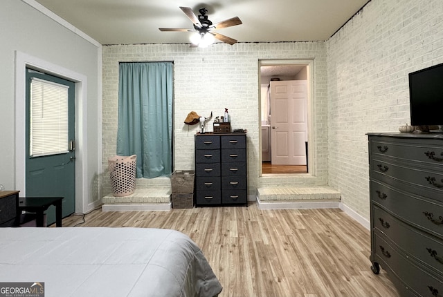 bedroom featuring brick wall, ceiling fan, and light wood finished floors