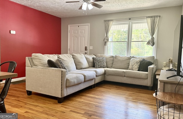 living area with a textured ceiling, wood finished floors, a ceiling fan, and baseboards