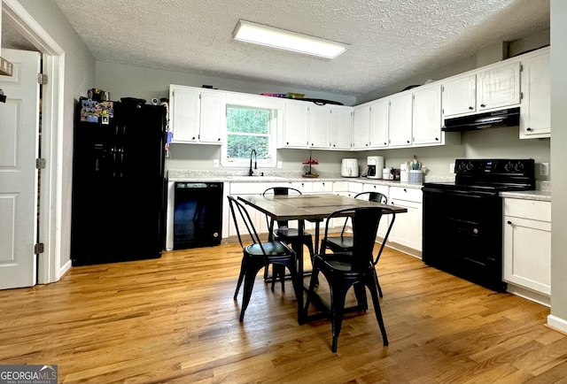 kitchen featuring white cabinets, under cabinet range hood, light countertops, black appliances, and a sink