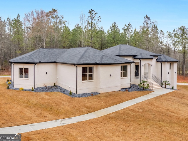 view of front of house featuring brick siding, a front yard, and roof with shingles