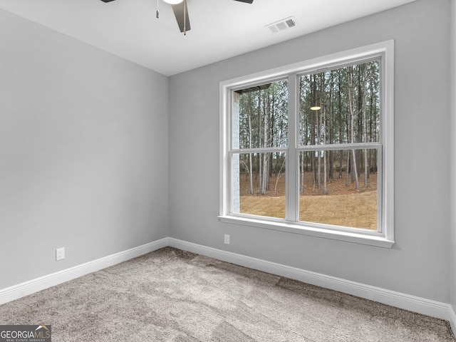 carpeted spare room featuring visible vents, ceiling fan, and baseboards