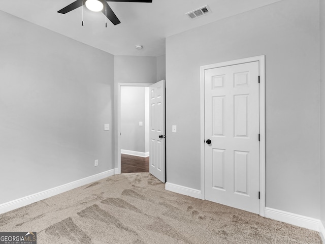 unfurnished bedroom with carpet floors, visible vents, baseboards, and a ceiling fan