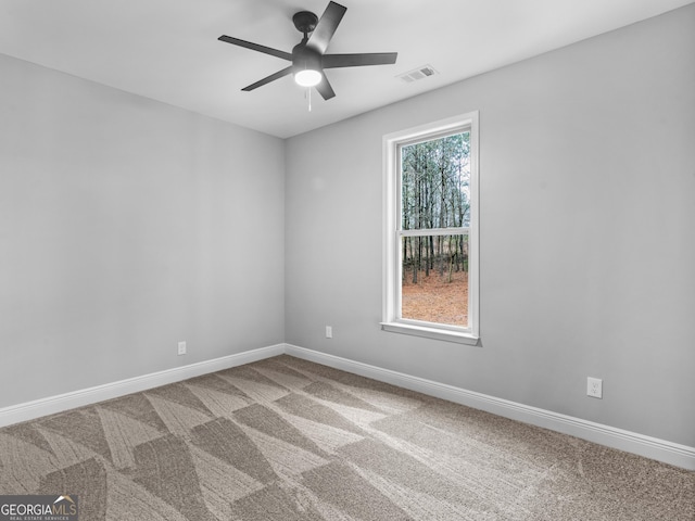 carpeted spare room featuring baseboards, visible vents, and a ceiling fan