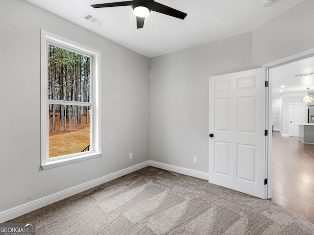 carpeted empty room featuring ceiling fan, visible vents, and baseboards