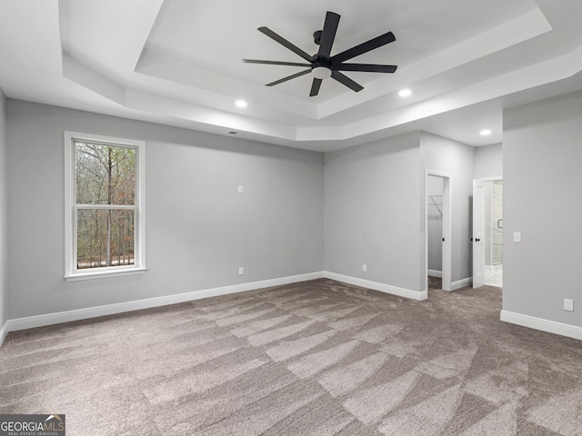 spare room with a tray ceiling, baseboards, carpet, and recessed lighting