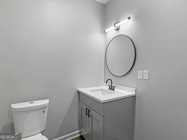 bathroom with toilet, vanity, and baseboards