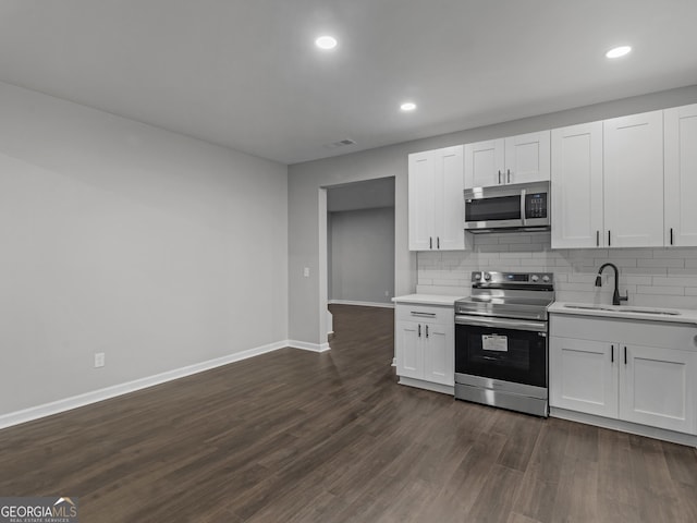 kitchen with a sink, white cabinetry, light countertops, appliances with stainless steel finishes, and dark wood finished floors