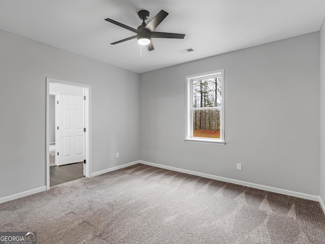 unfurnished room featuring ceiling fan, dark carpet, visible vents, and baseboards