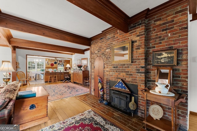 living area with ornamental molding, beamed ceiling, and wood-type flooring