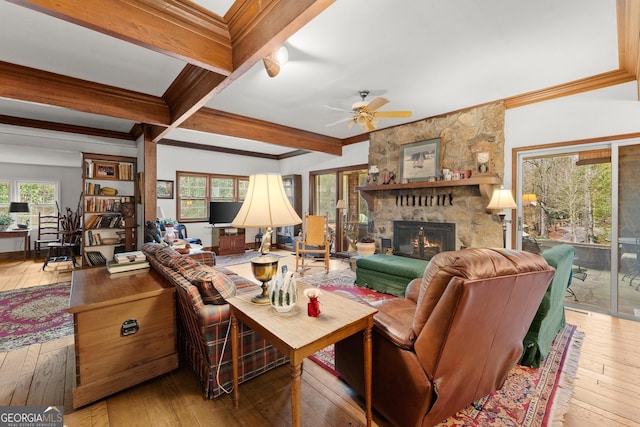 living area with wood-type flooring, a fireplace, crown molding, and beamed ceiling