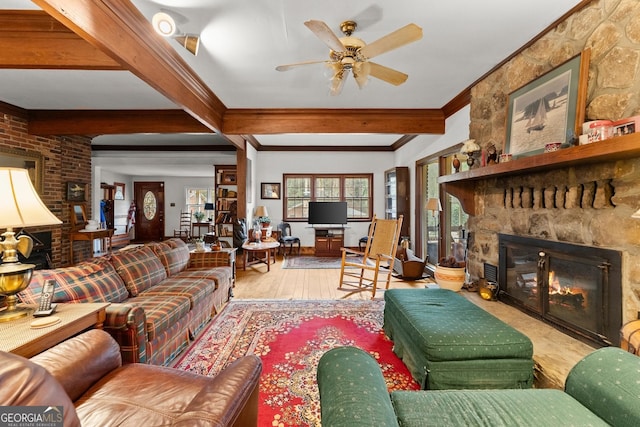 living area featuring ceiling fan, wood finished floors, crown molding, a fireplace, and beam ceiling