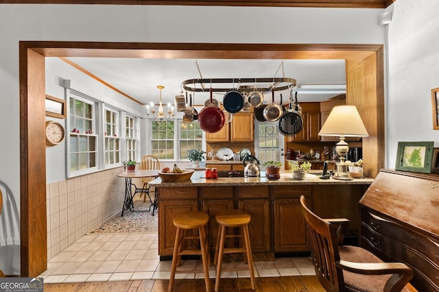 interior space with crown molding, tile walls, an inviting chandelier, and light tile patterned floors