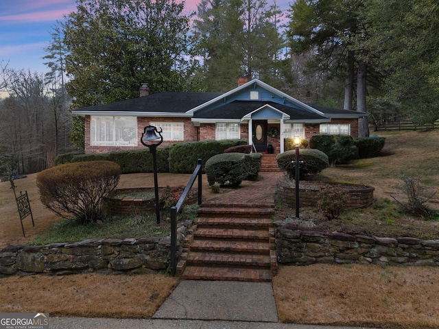 view of front facade with brick siding and a chimney