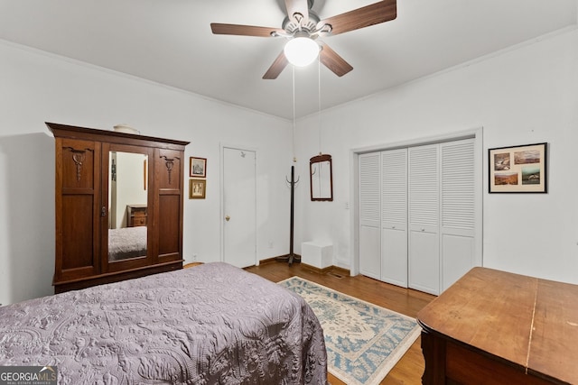 bedroom with ornamental molding, a closet, wood finished floors, and a ceiling fan