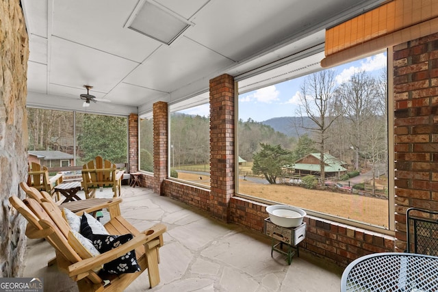 sunroom / solarium featuring ceiling fan and a mountain view