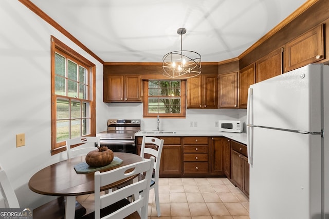 kitchen with white appliances, brown cabinetry, a sink, and an inviting chandelier