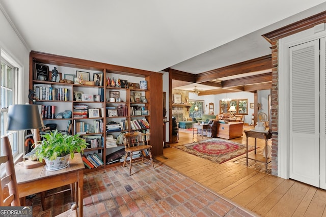 sitting room featuring an inviting chandelier, a fireplace, beam ceiling, and hardwood / wood-style flooring