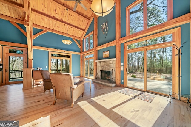 living room with wood ceiling, wood finished floors, beamed ceiling, a fireplace, and high vaulted ceiling