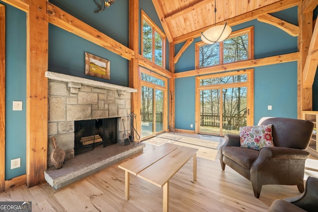 living room featuring beam ceiling, a fireplace, wood ceiling, wood finished floors, and baseboards