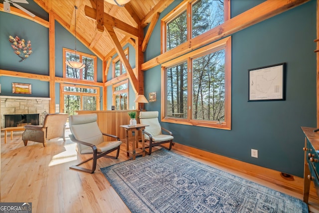 sitting room with high vaulted ceiling, a stone fireplace, wood finished floors, wood ceiling, and beam ceiling