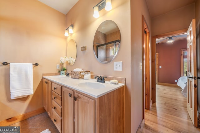 bathroom with connected bathroom, a sink, baseboards, and double vanity